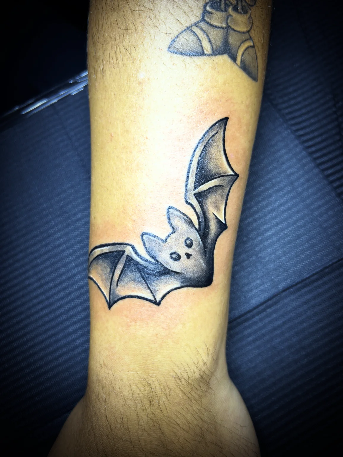 Black and grey cartoon bat tattoo on wrist