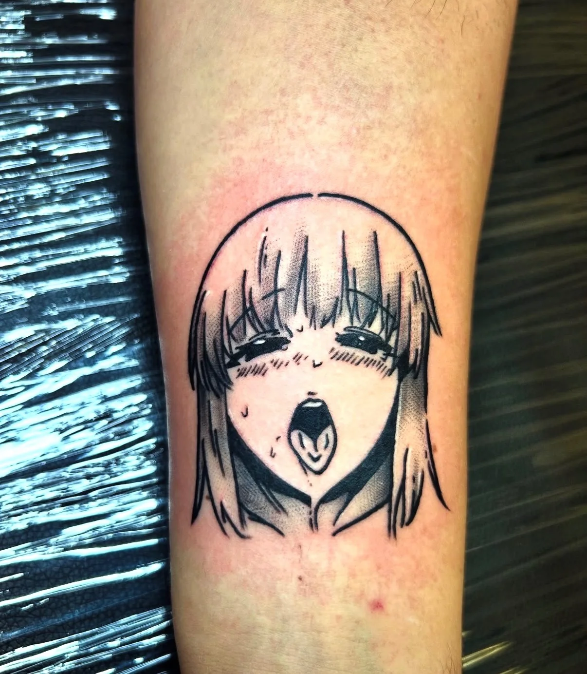 Black ink anime manga face tattoo on forearm