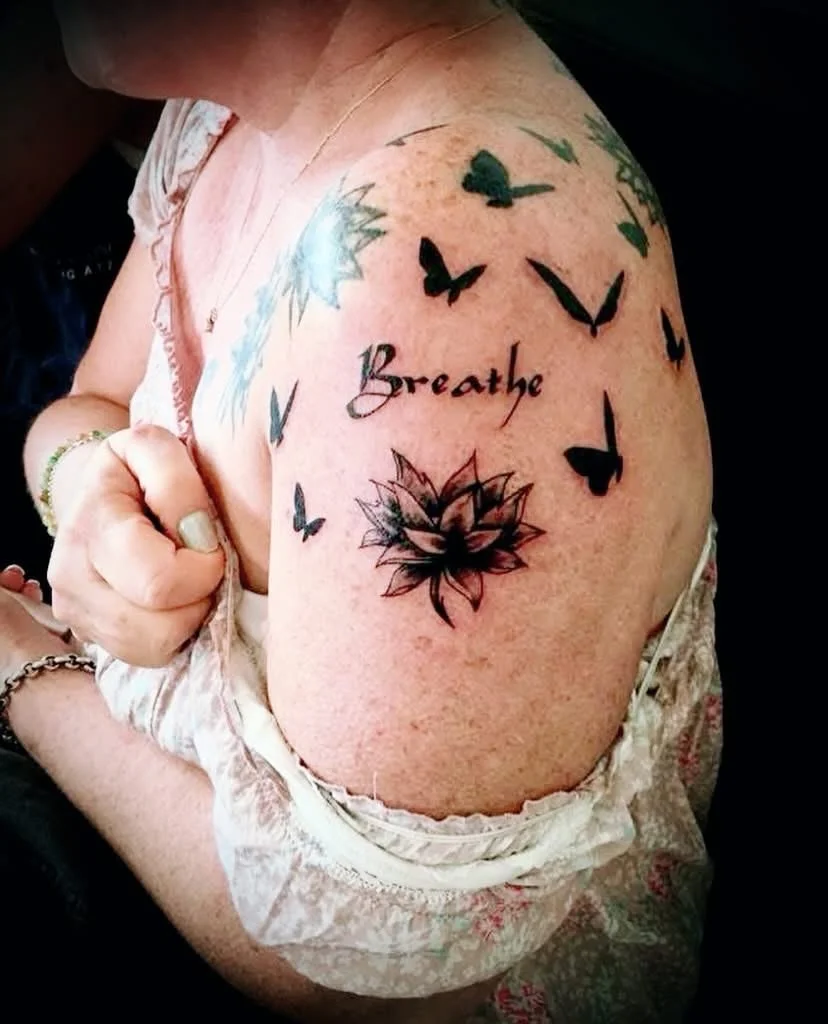 Blackwork butterflies and lotus with script on upper arm