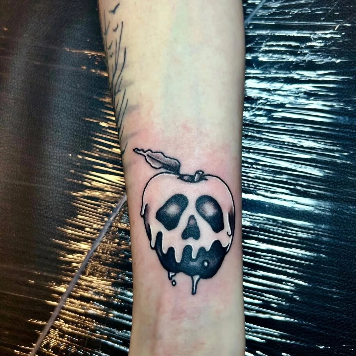 Neo-traditional poison apple skull tattoo on forearm