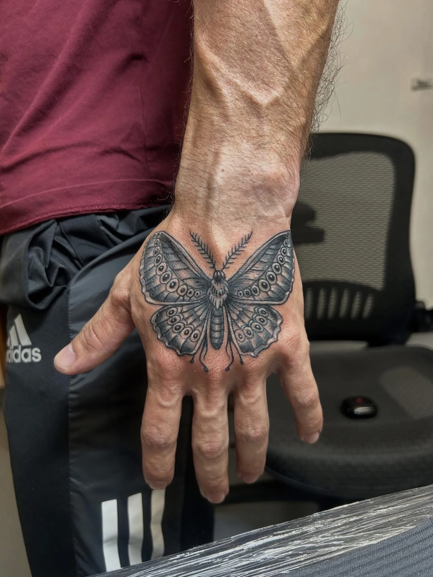 Black and grey moth tattoo on the back of hand