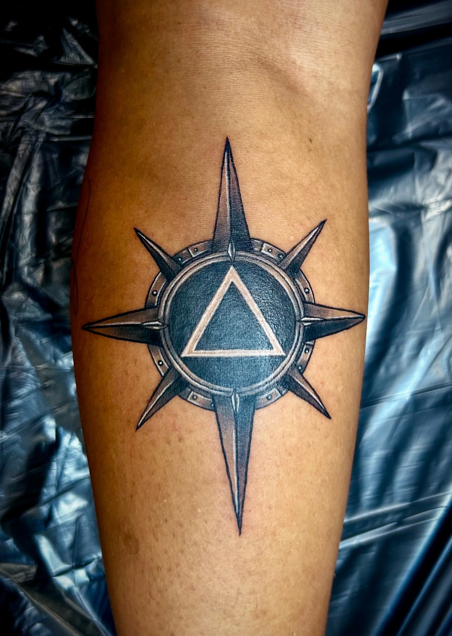 Black and grey compass star with triangle emblem on forearm