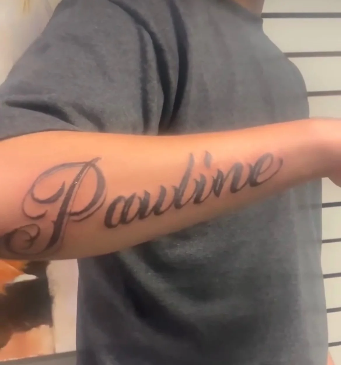 Black script name tattoo reading Pauline on forearm