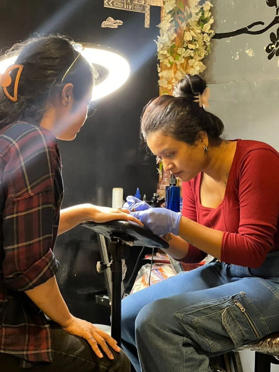 Tattoo artist applying tattoo to client forearm in studio