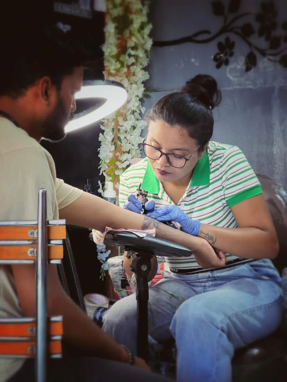 Fine line tattoo being applied to client forearm in studio