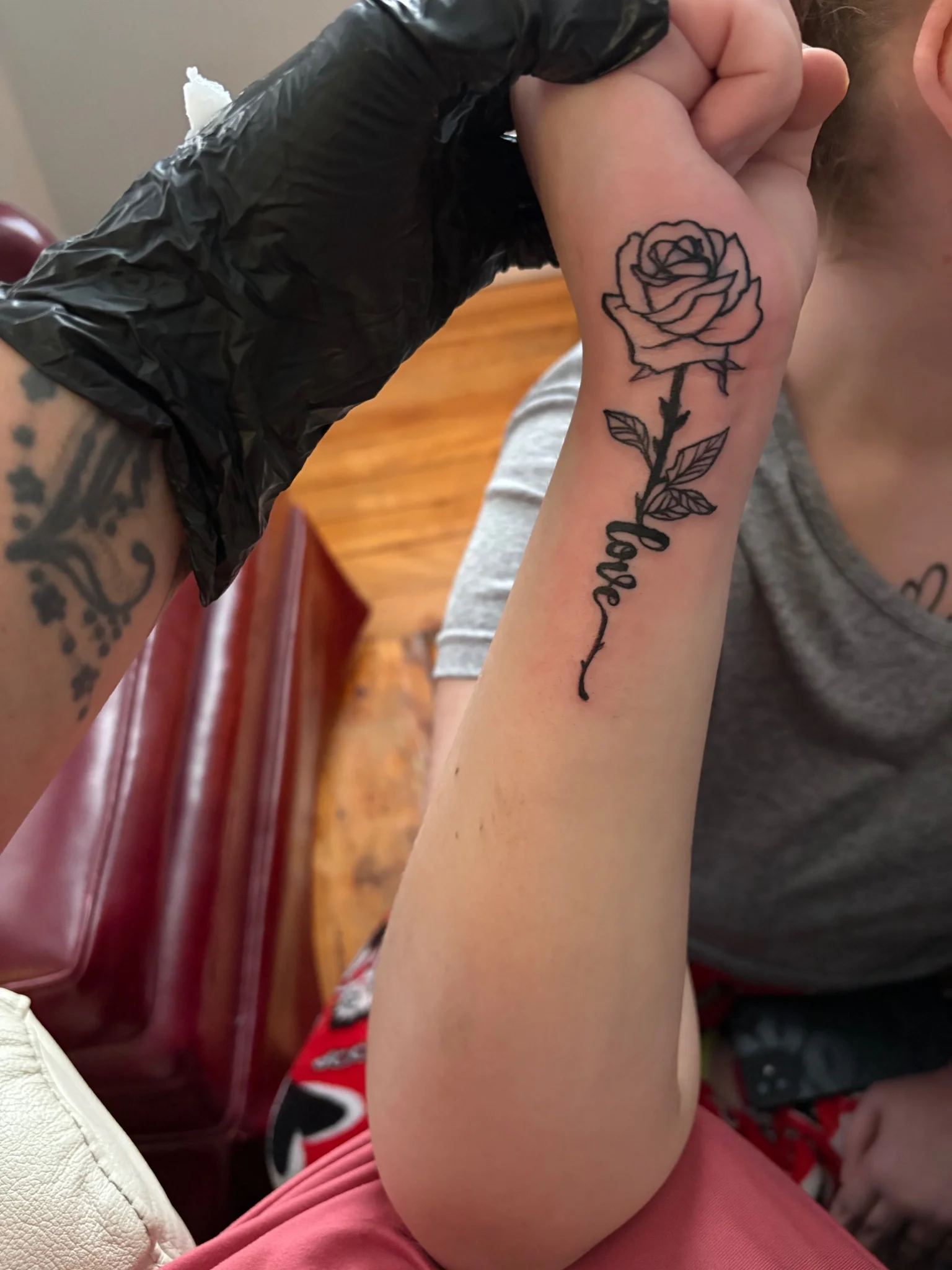 Fine line rose and script love tattoo on forearm