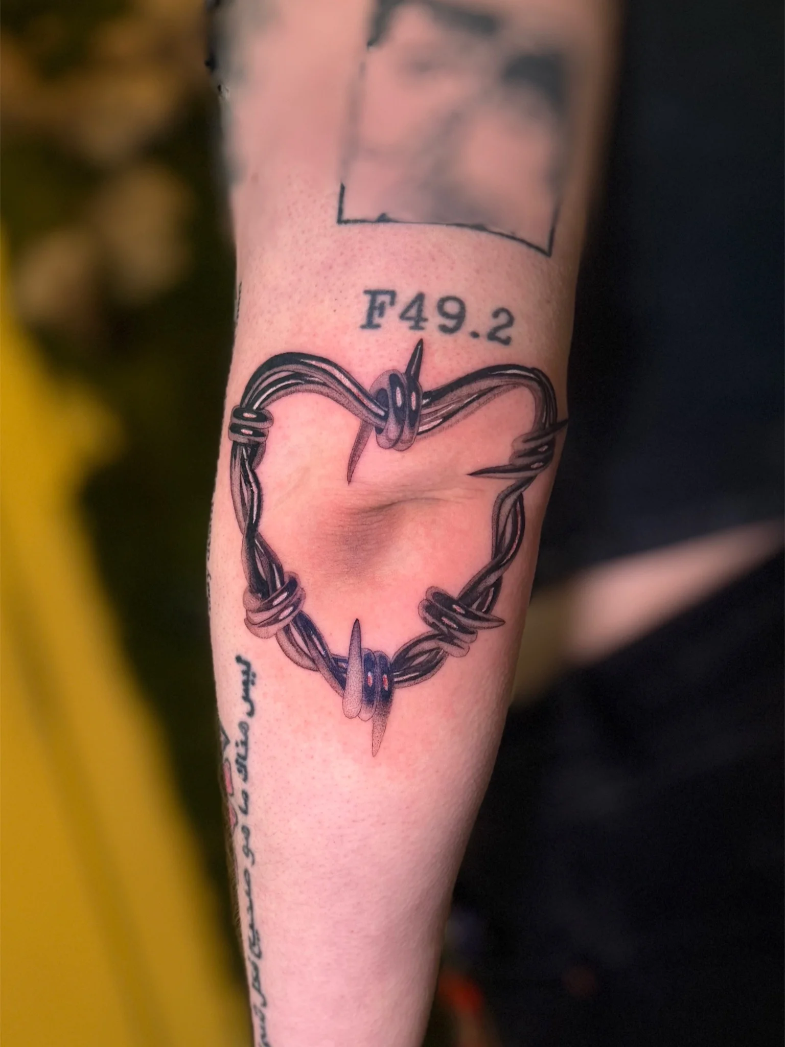Black and grey barbed wire heart tattoo on forearm