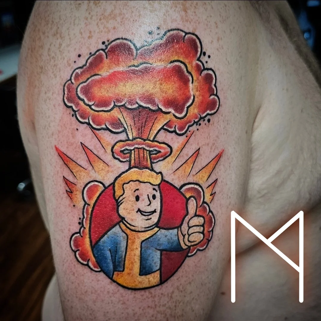Colorful Fallout Vault Boy with mushroom cloud tattoo on upper arm