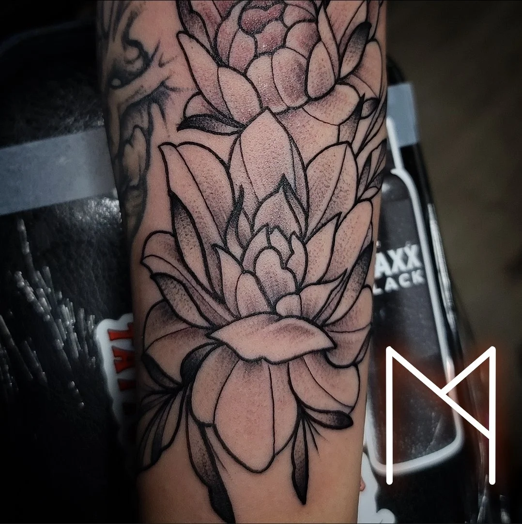 Neo-traditional lotus flower tattoo on arm with black and pink shading