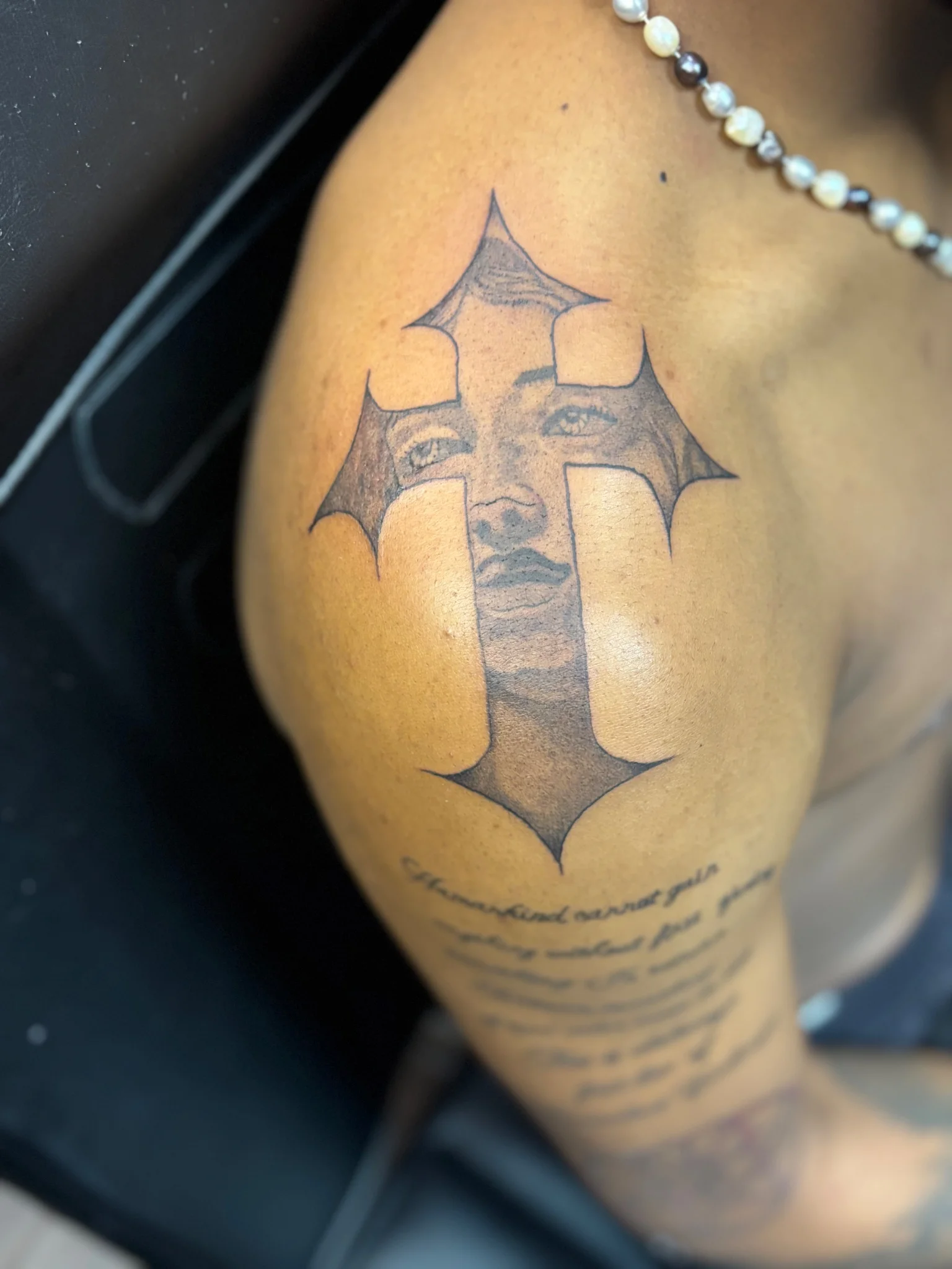 Black and grey Chicano cross with portrait tattoo on shoulder