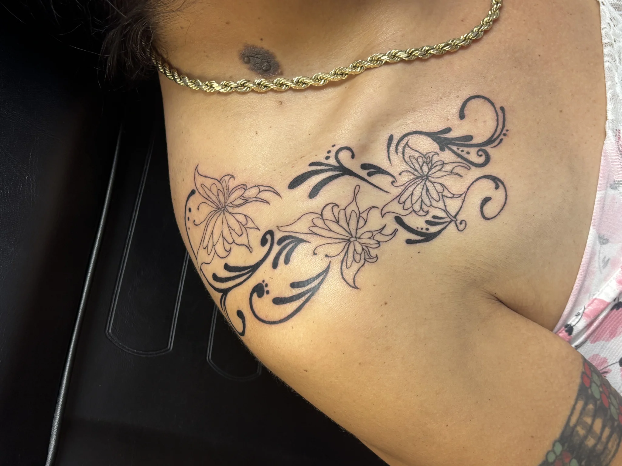 Black floral and swirl tattoo across the chest