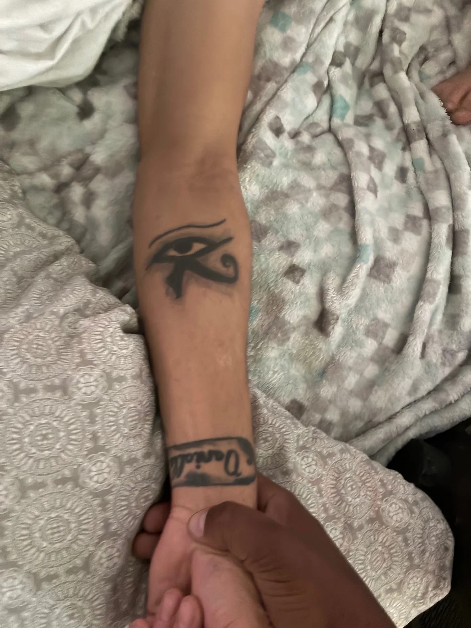 Blackwork Eye of Horus and script name tattoo on forearm