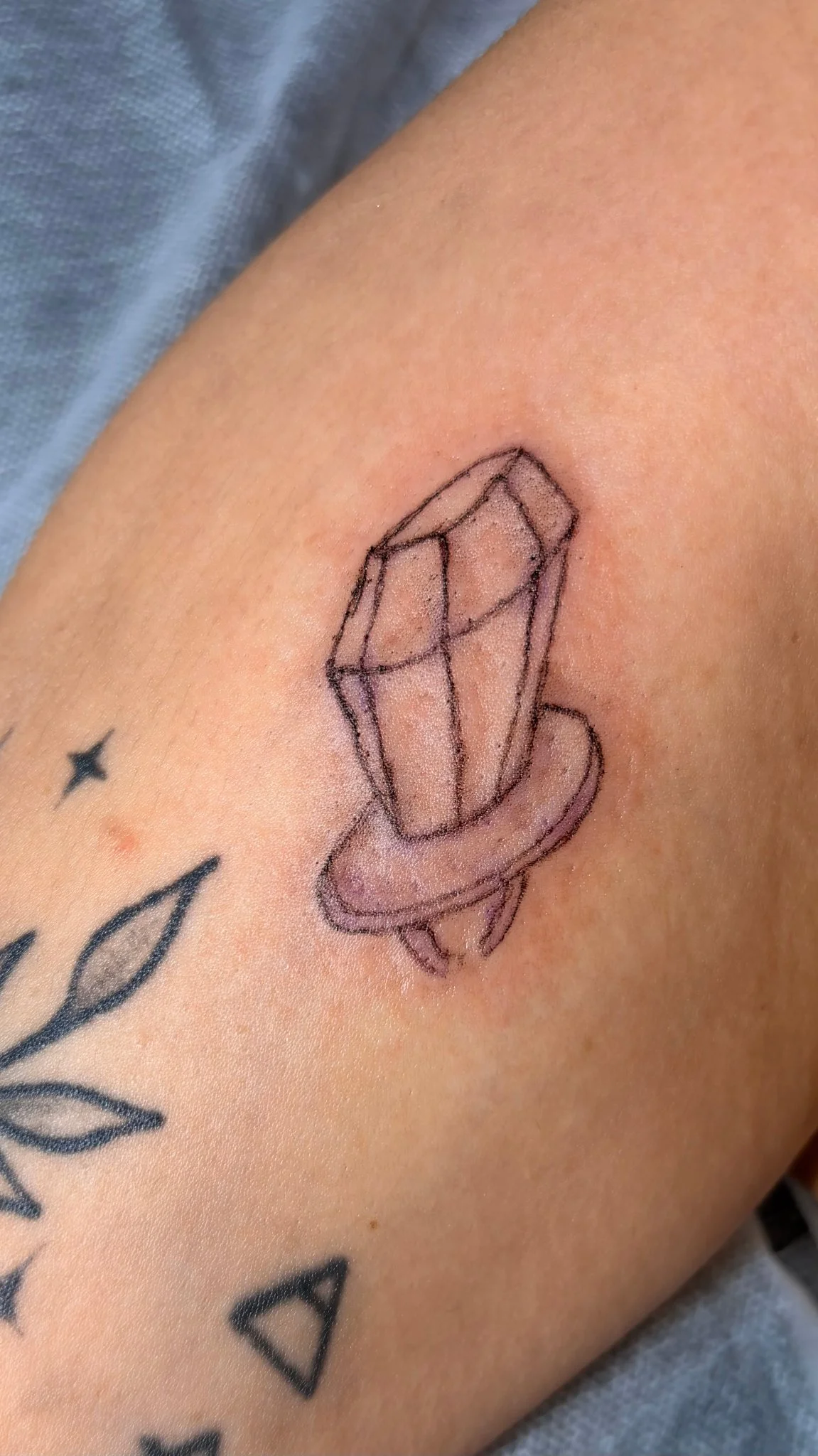 Fine line crystal with ribbon tattoo on forearm
