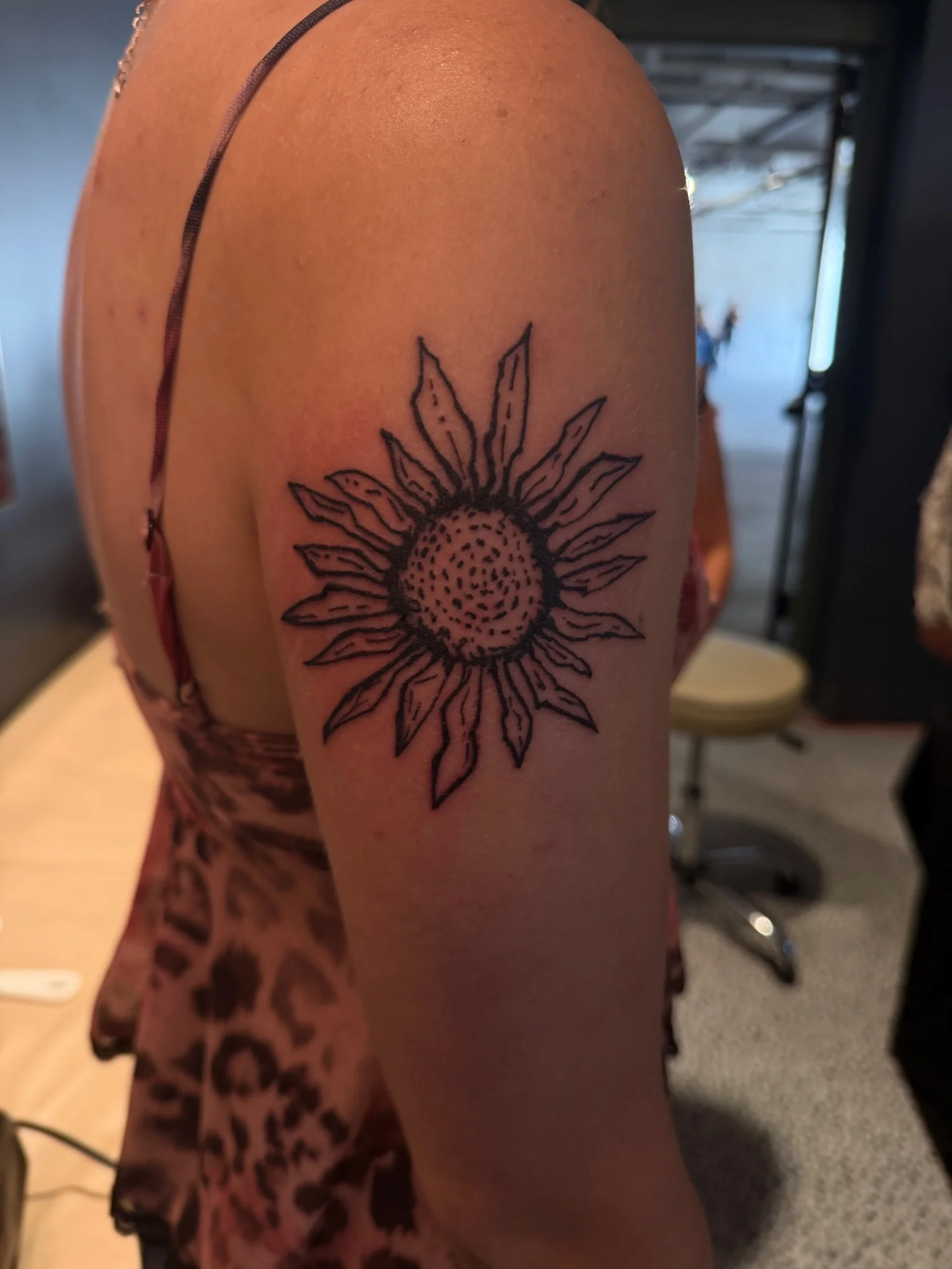 Black outline sunflower tattoo on upper arm