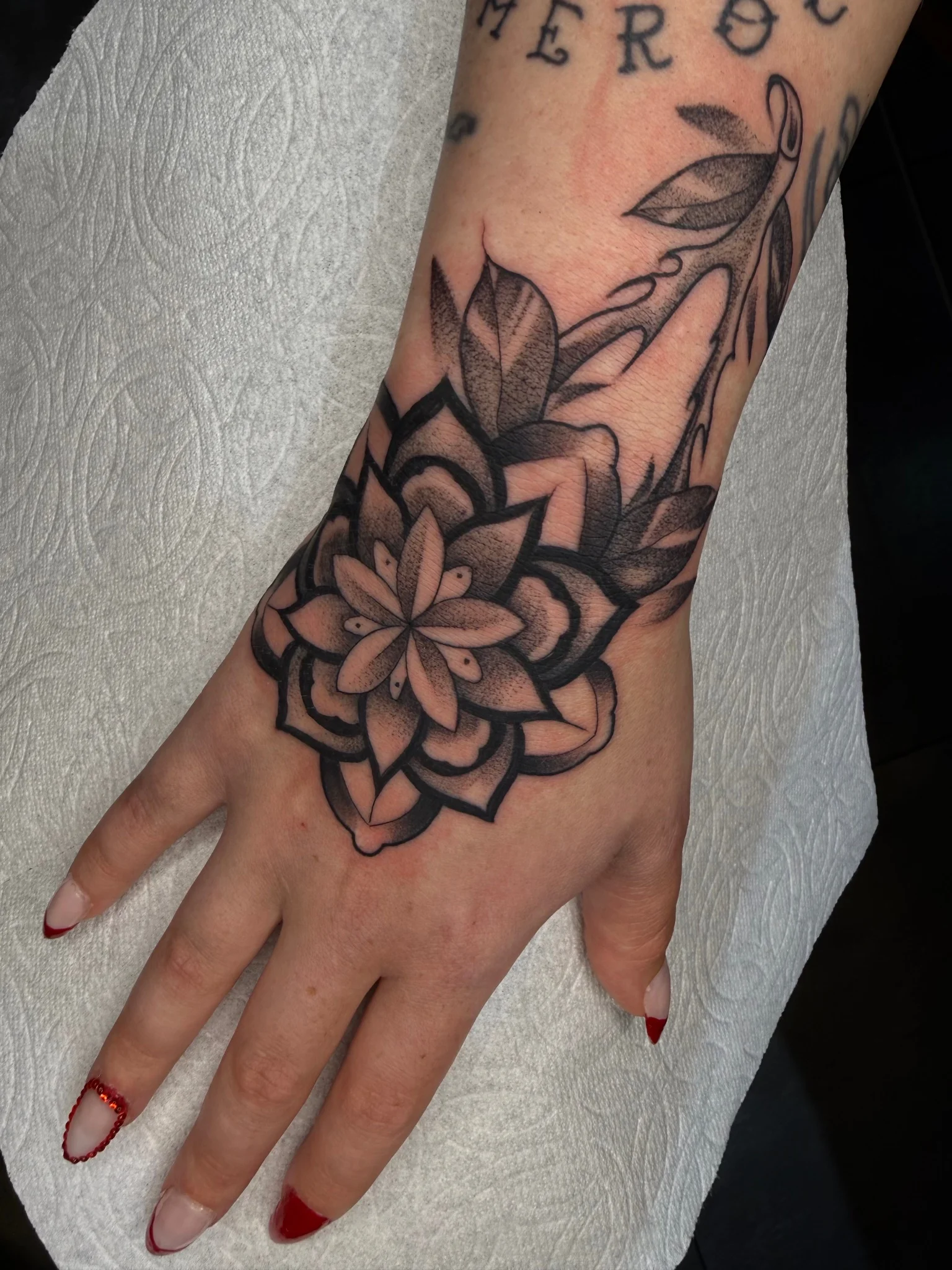 Black and grey mandala flower tattoo on hand and wrist