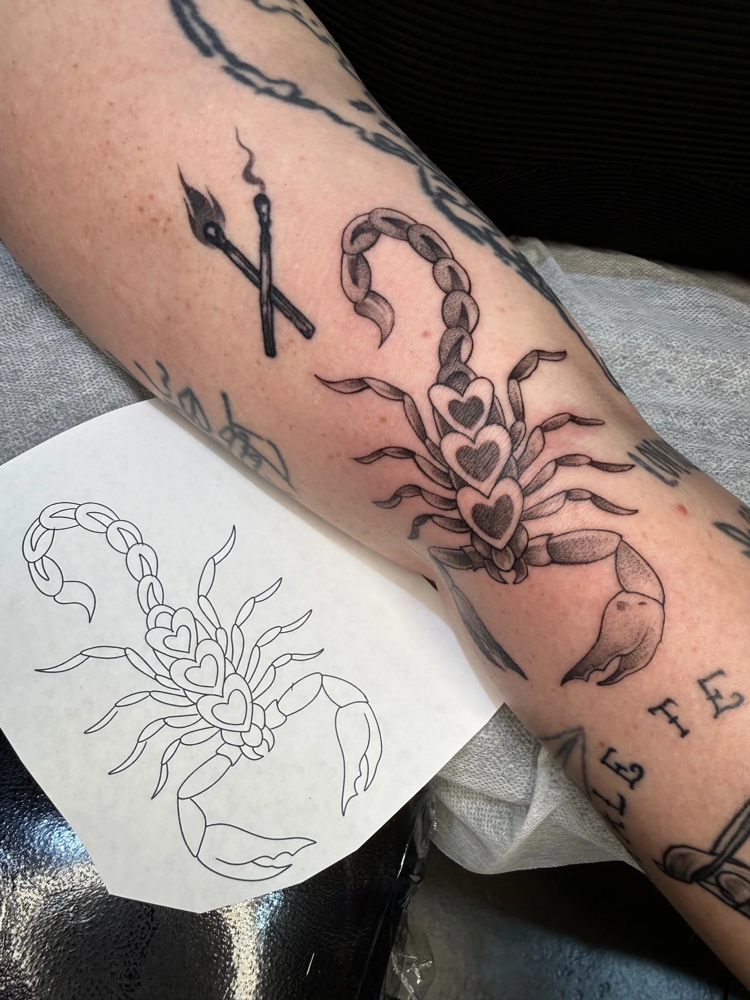 Neo-traditional scorpion with heart motifs tattooed on forearm
