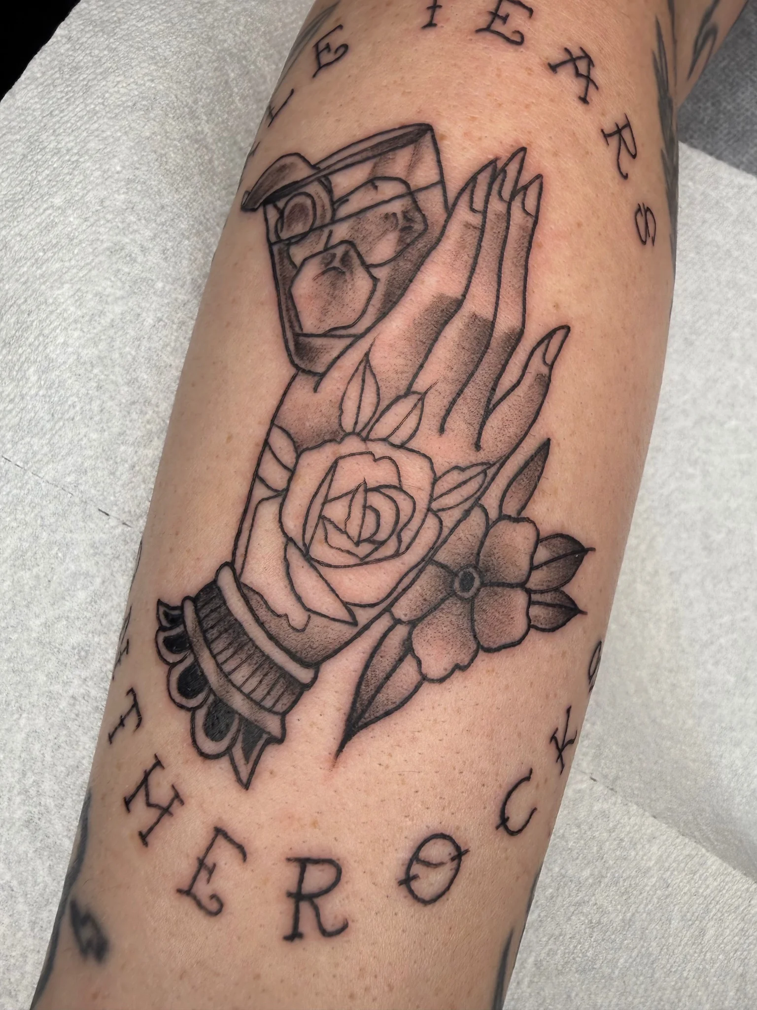 Neo-traditional praying hands with rose and floral tattoo on forearm