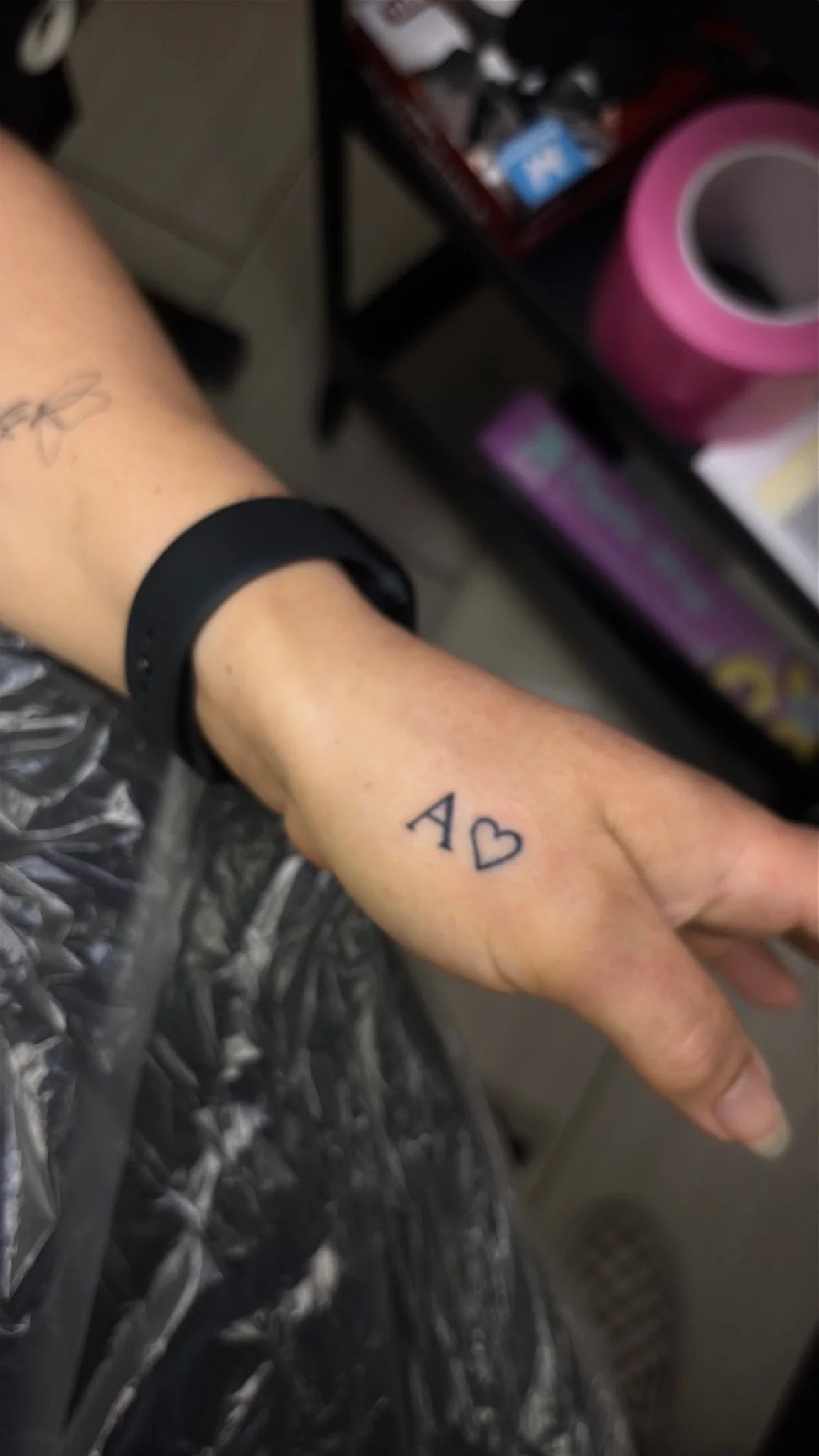 Minimalist letter A and heart outline tattoo on hand