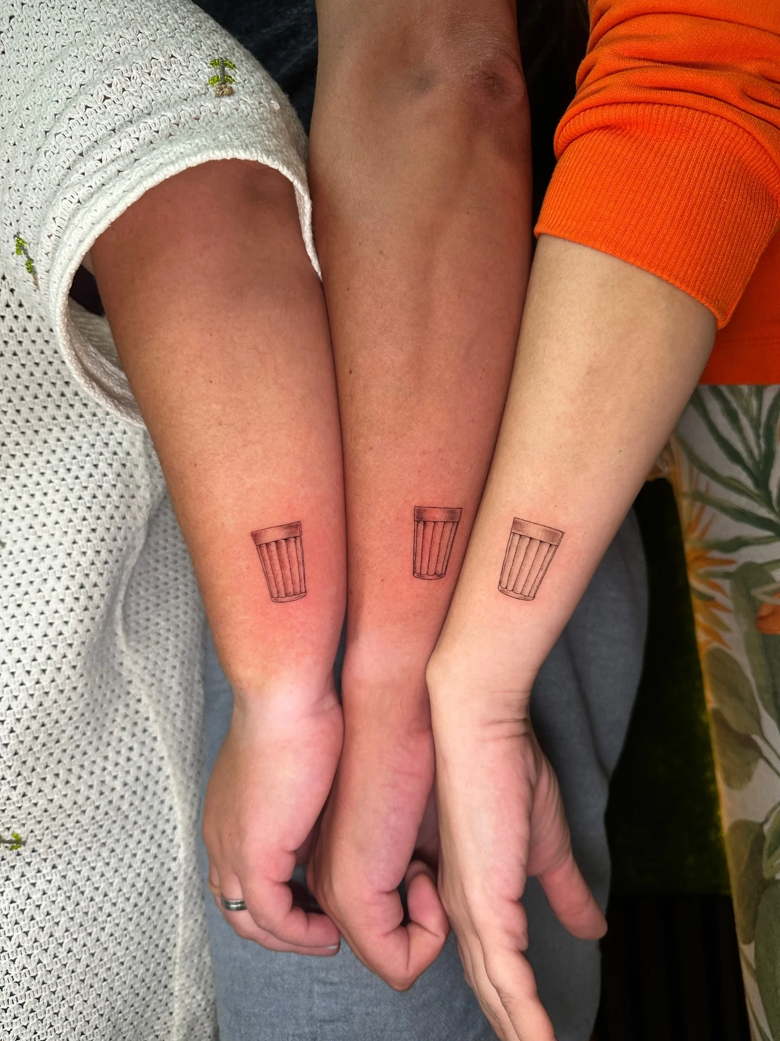 Matching fine line trash can tattoos on three wrists