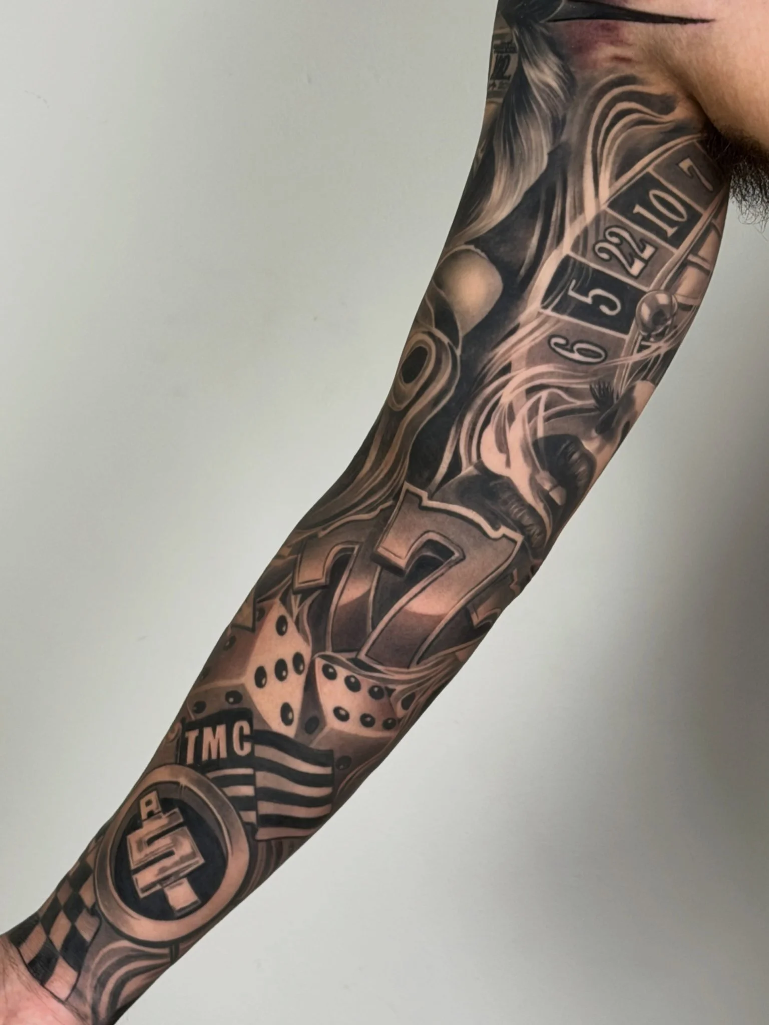 Black and grey casino themed full sleeve tattoo with dice and lucky 7