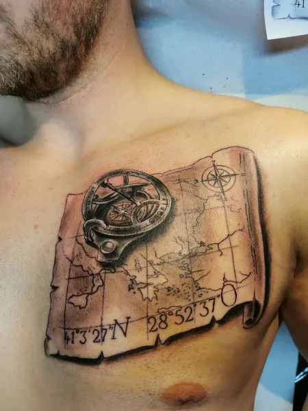 Black and grey vintage compass and map tattoo on chest with coordinates
