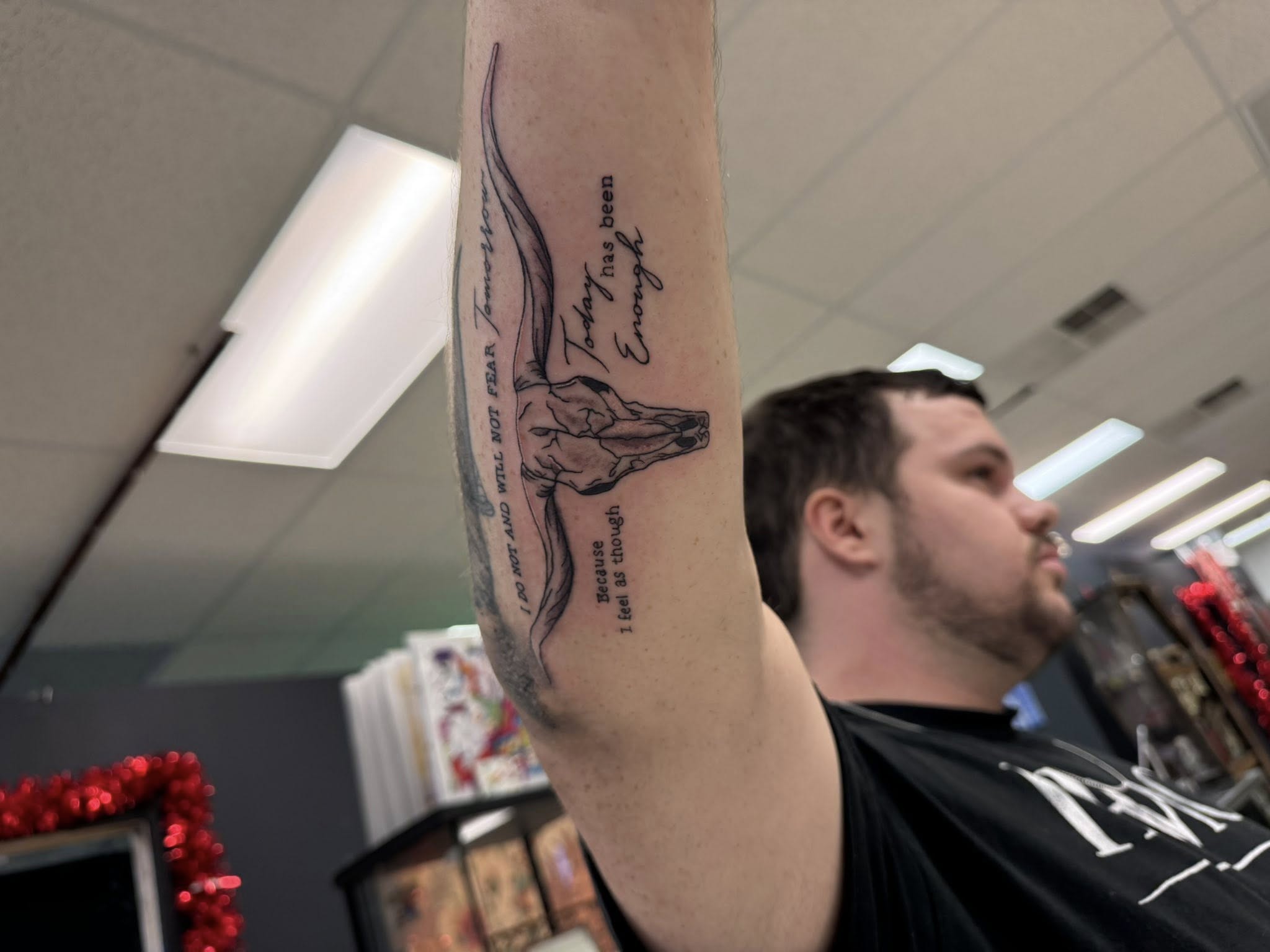 Black and grey deer head tattoo with script text on forearm