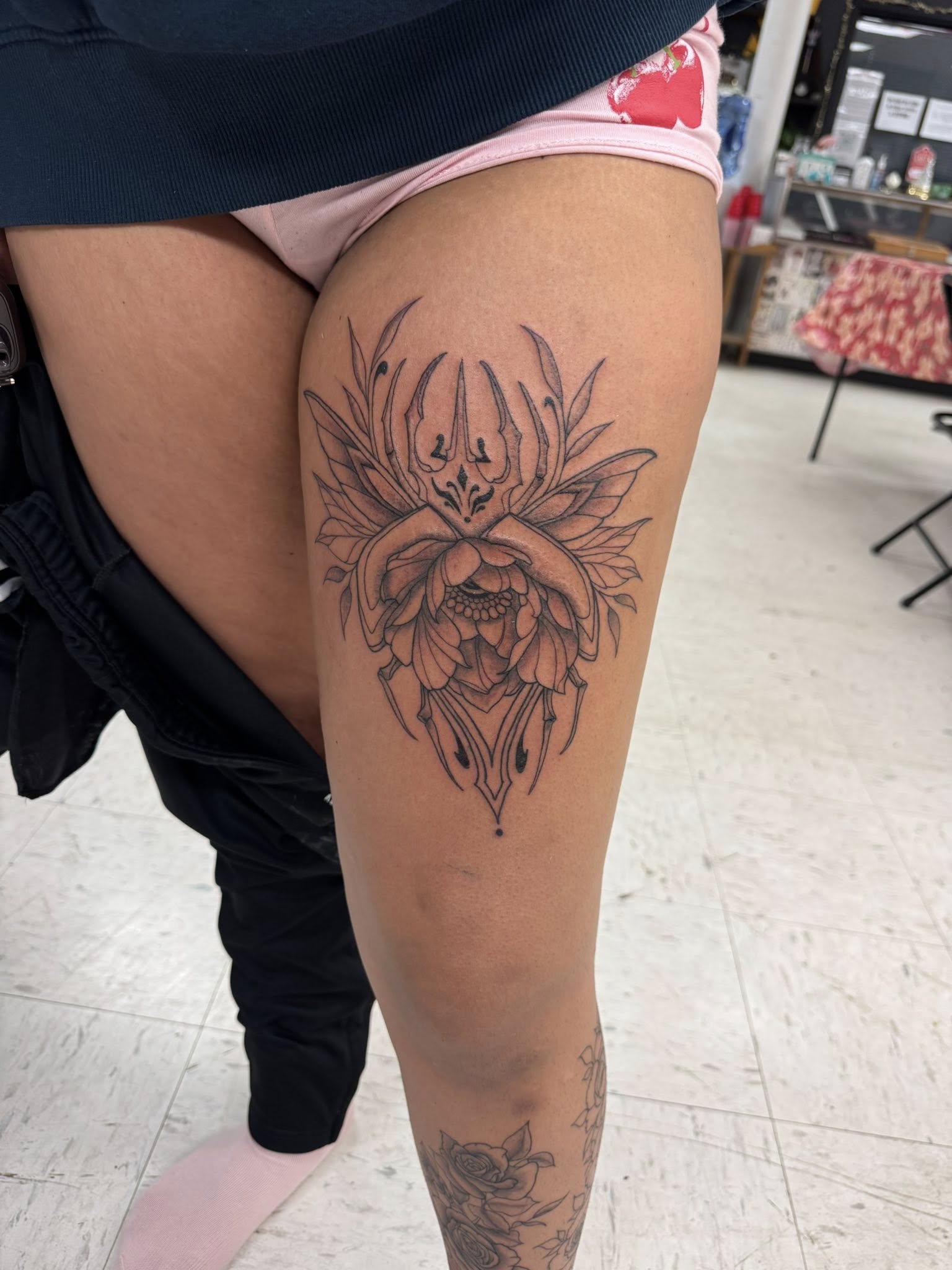 Detailed illustrative floral tattoo on upper thigh with ornate petals