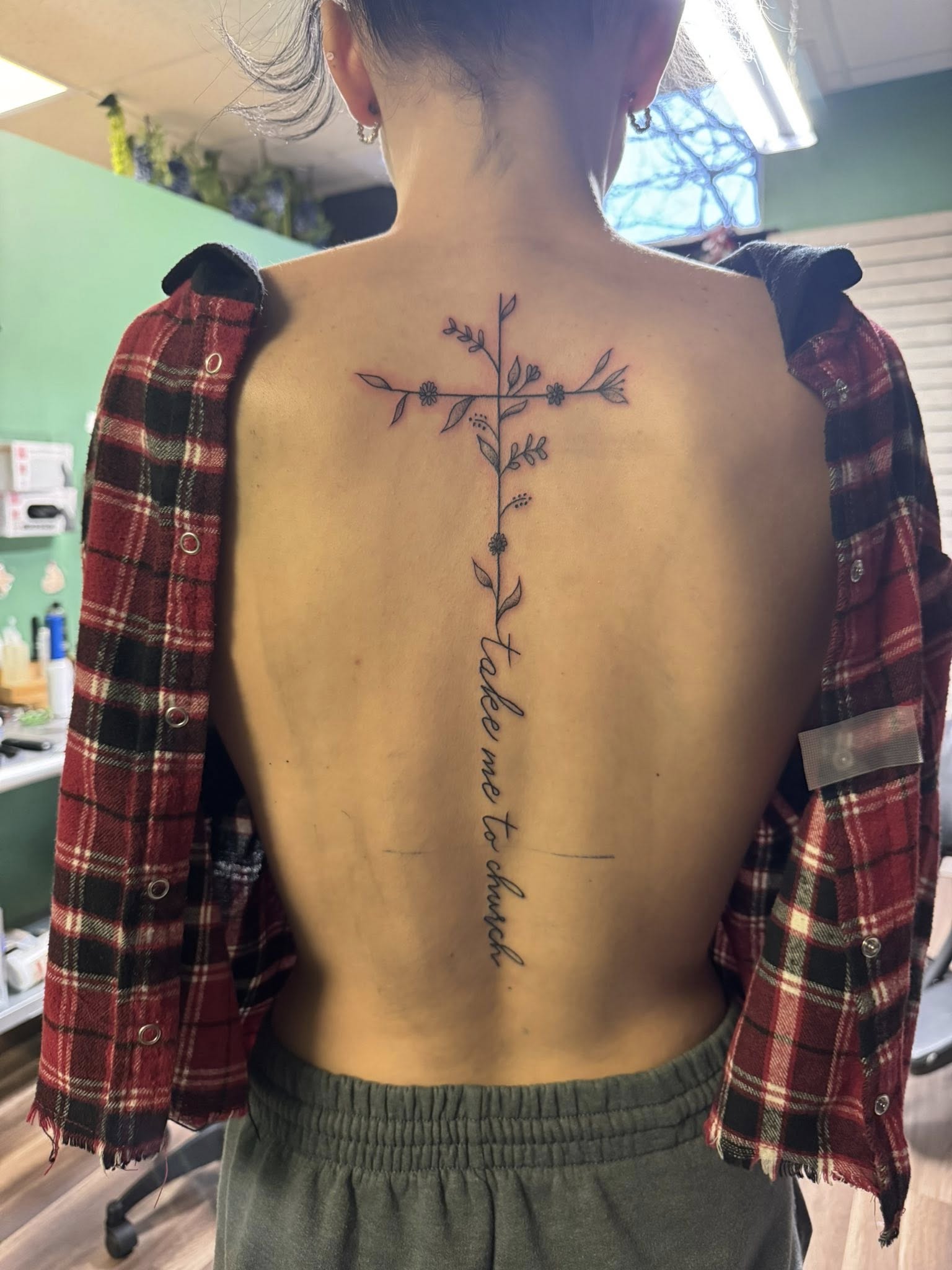 Fine line botanical branch with script lettering down spine tattoo