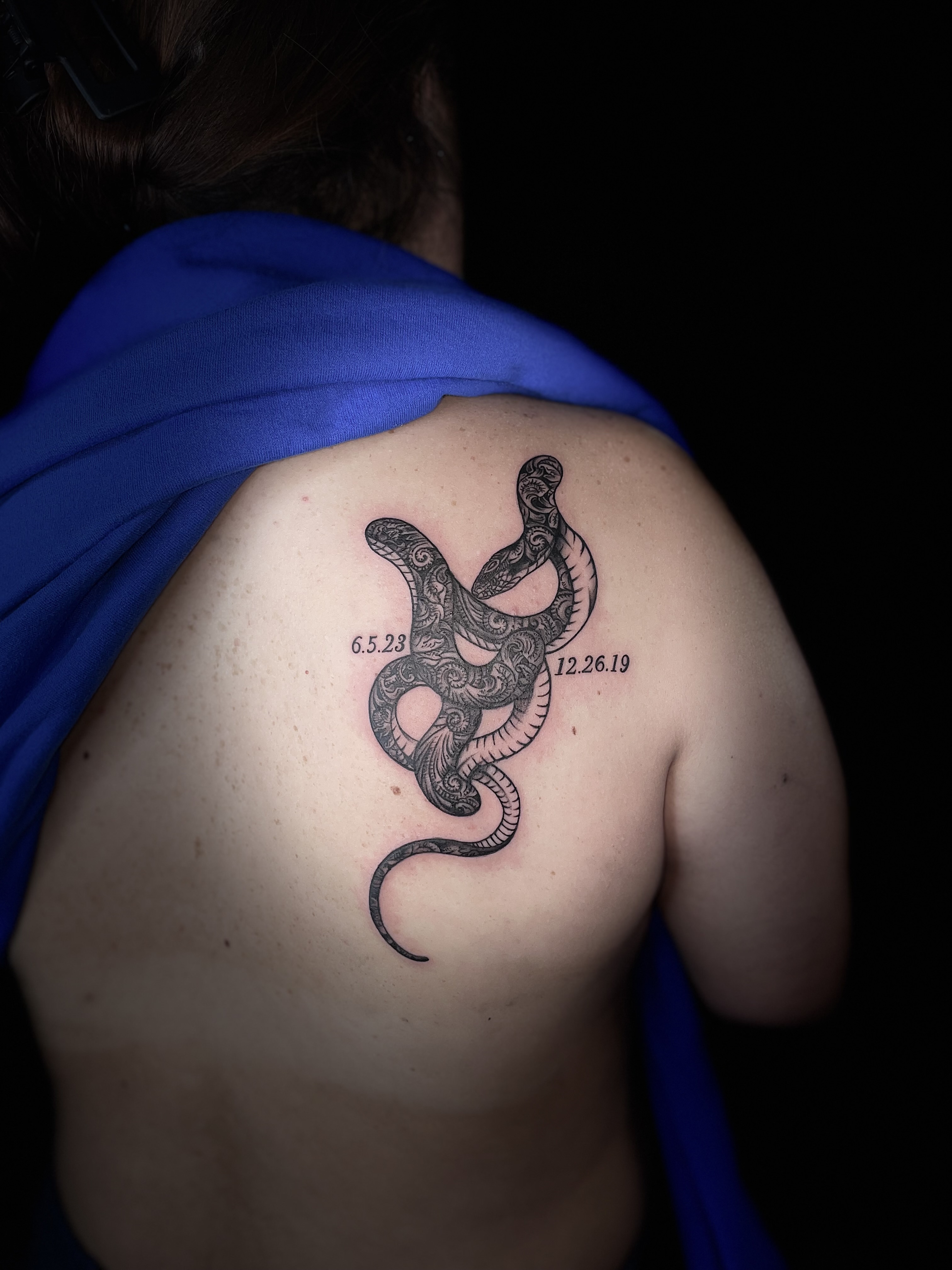 Ornamental snake tattoo with decorative details and dates on shoulder