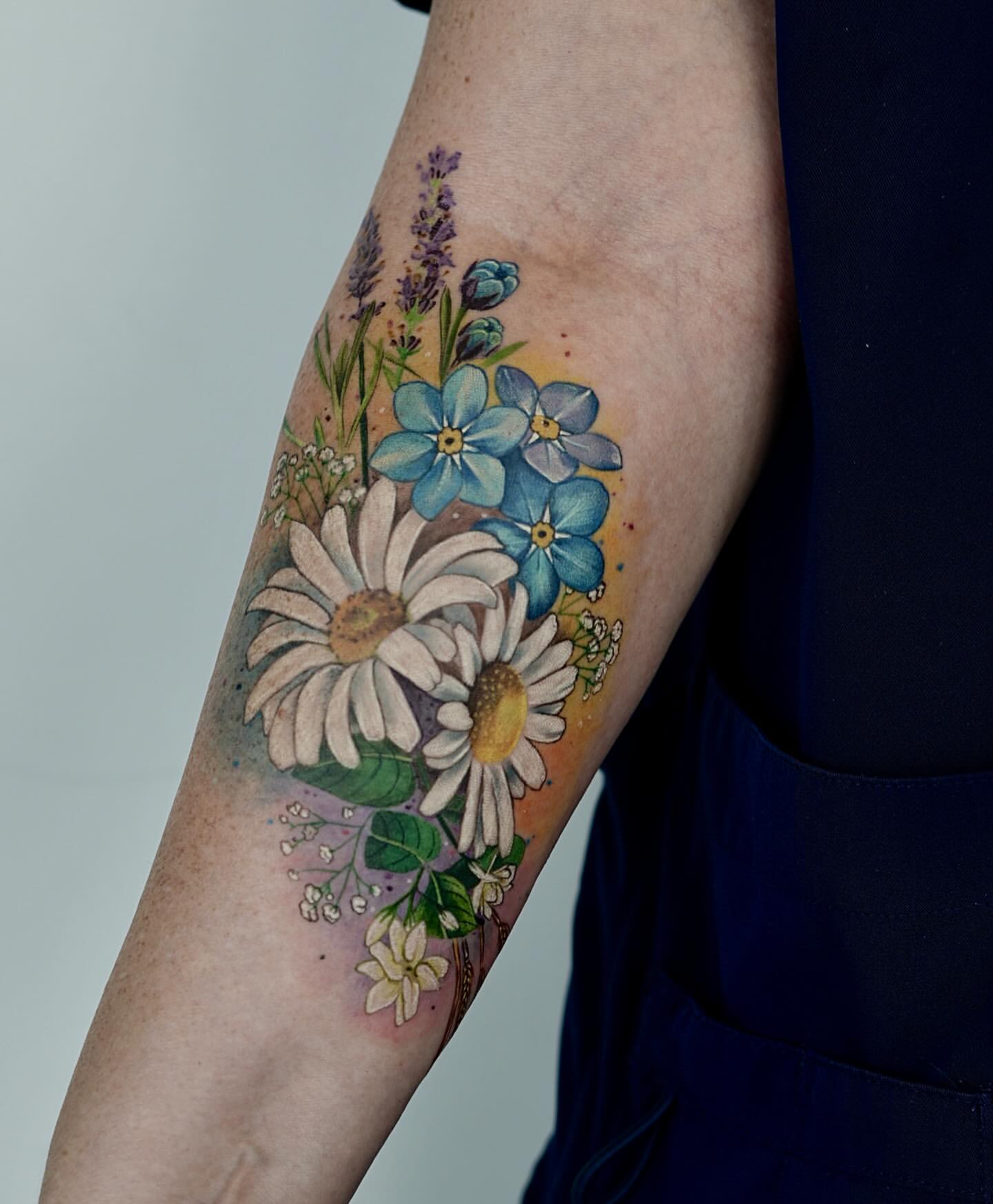Colorful botanical wildflower bouquet tattoo on forearm