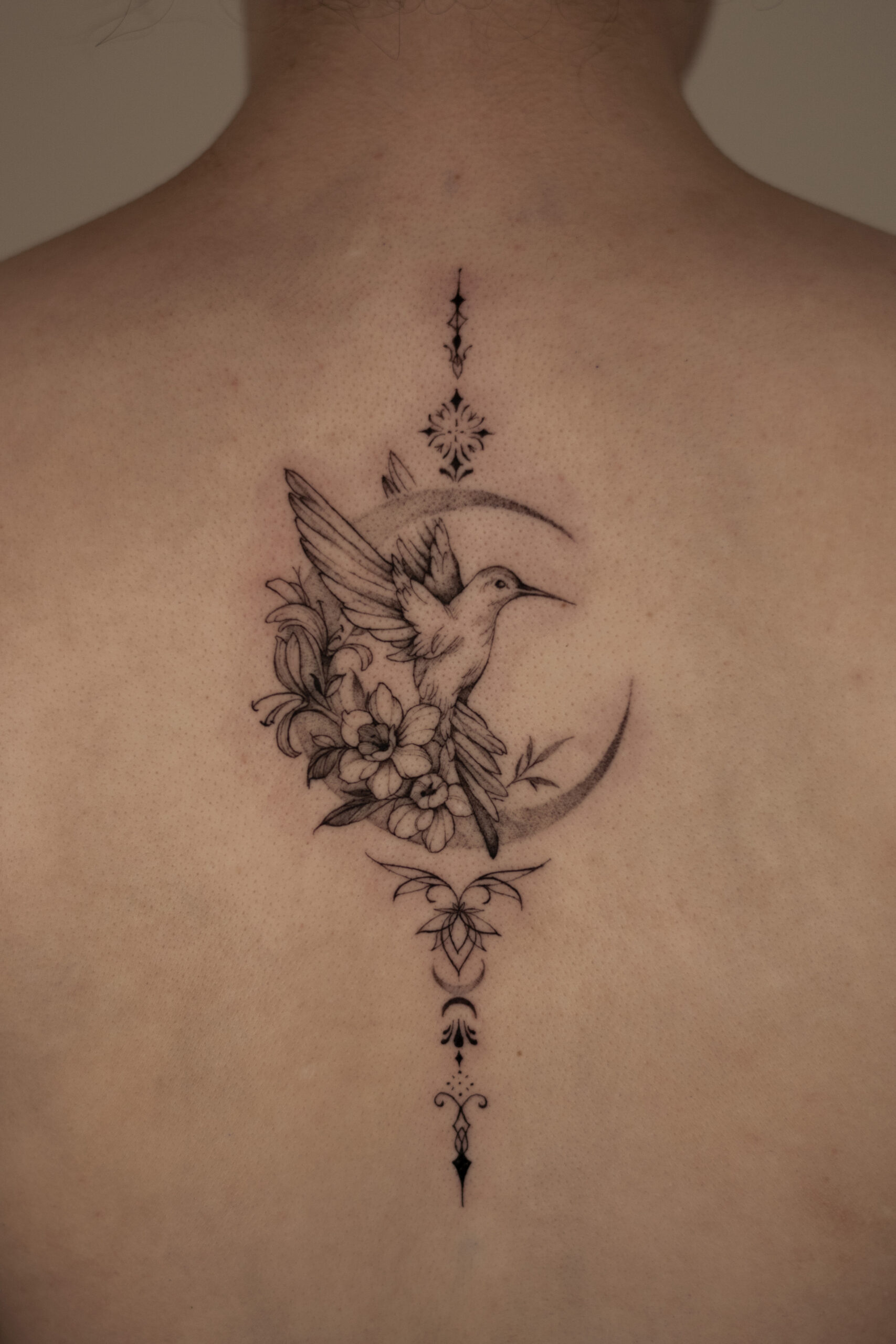 Fine line hummingbird with floral bouquet and ornamental details on back