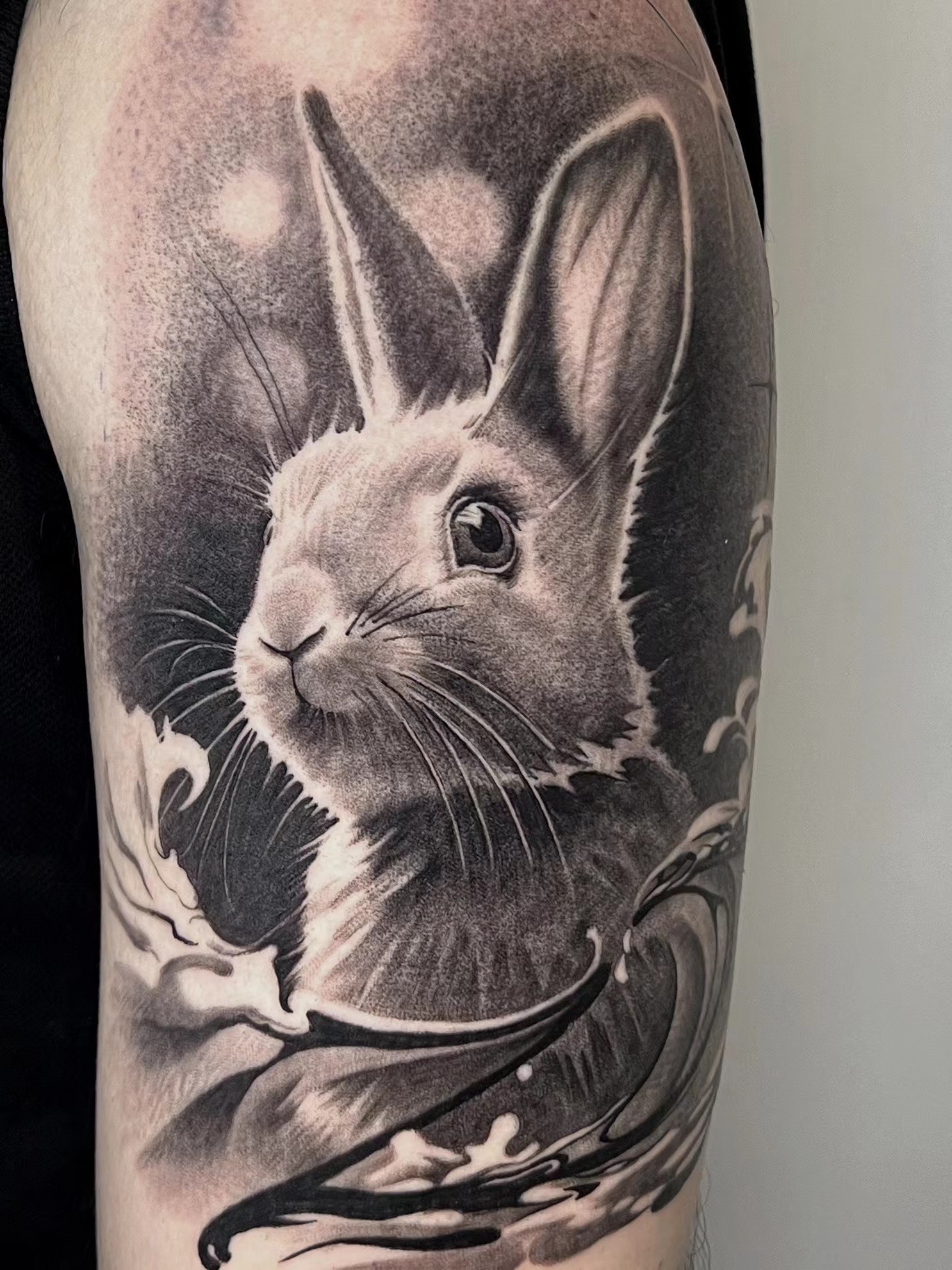 Black and grey realism rabbit portrait with ornamental flourishes on upper arm