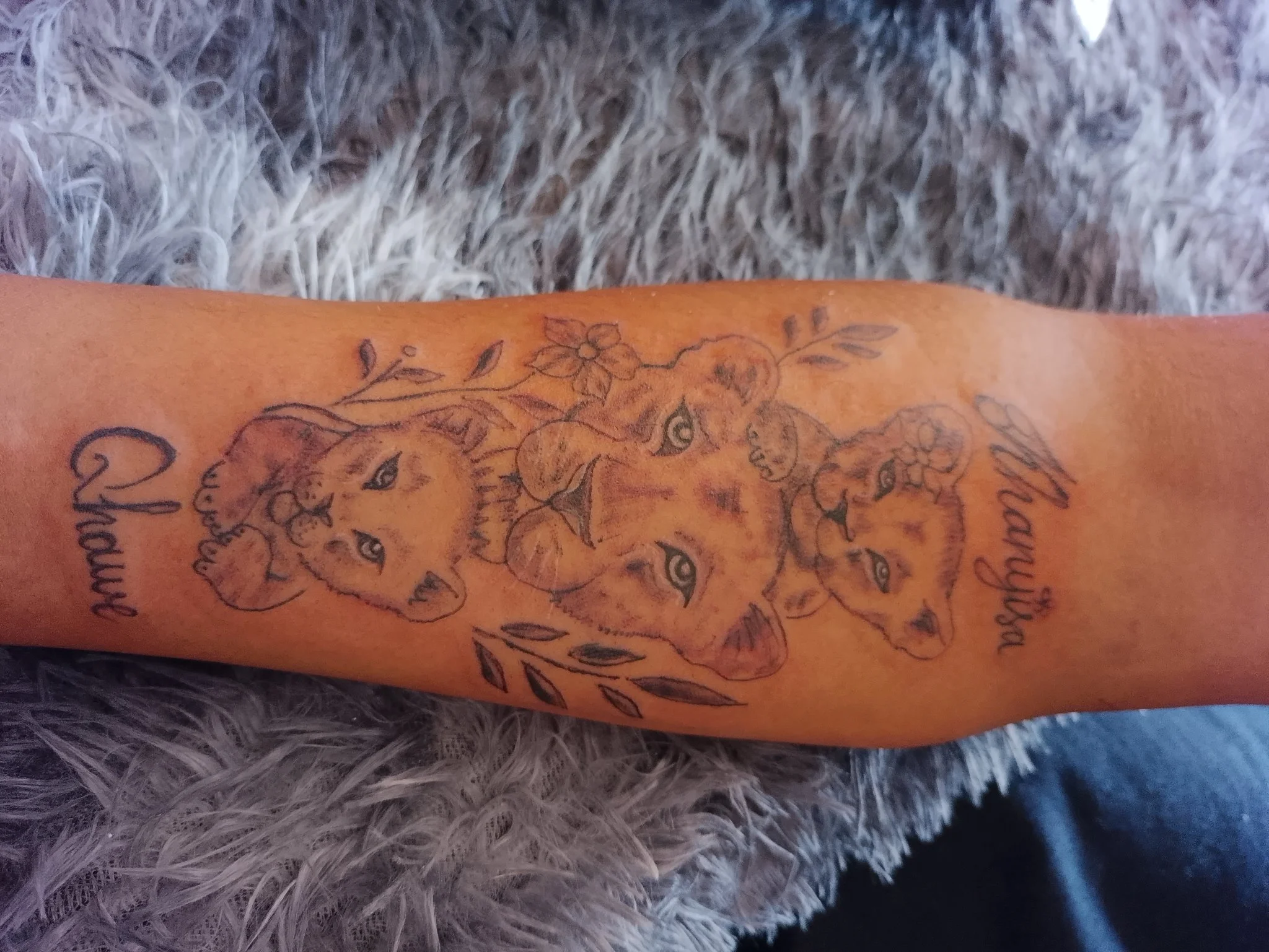 Illustrative cherub and floral design on forearm with script lettering