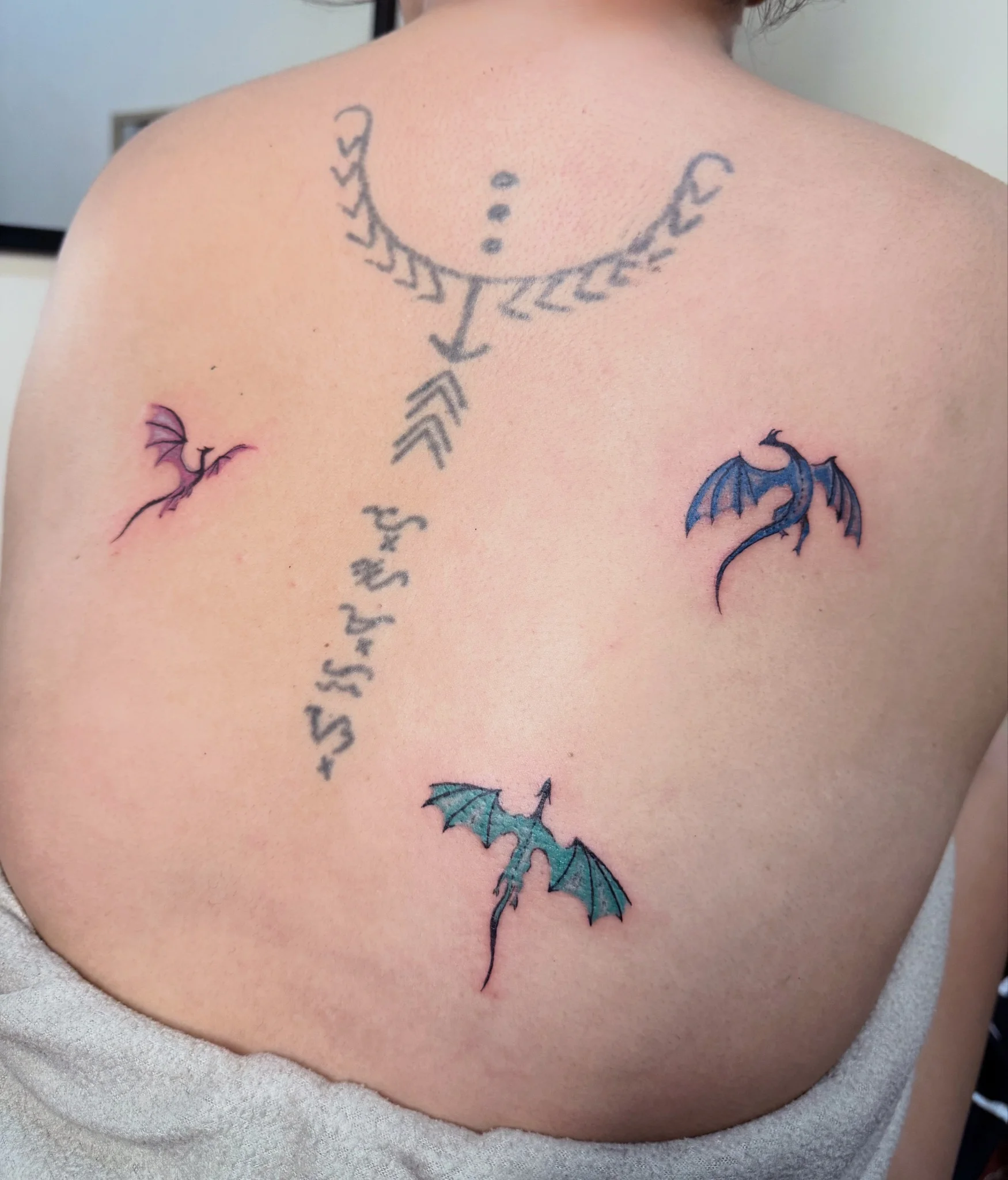 Illustrative dragon and bat wing tattoos with script lettering on back