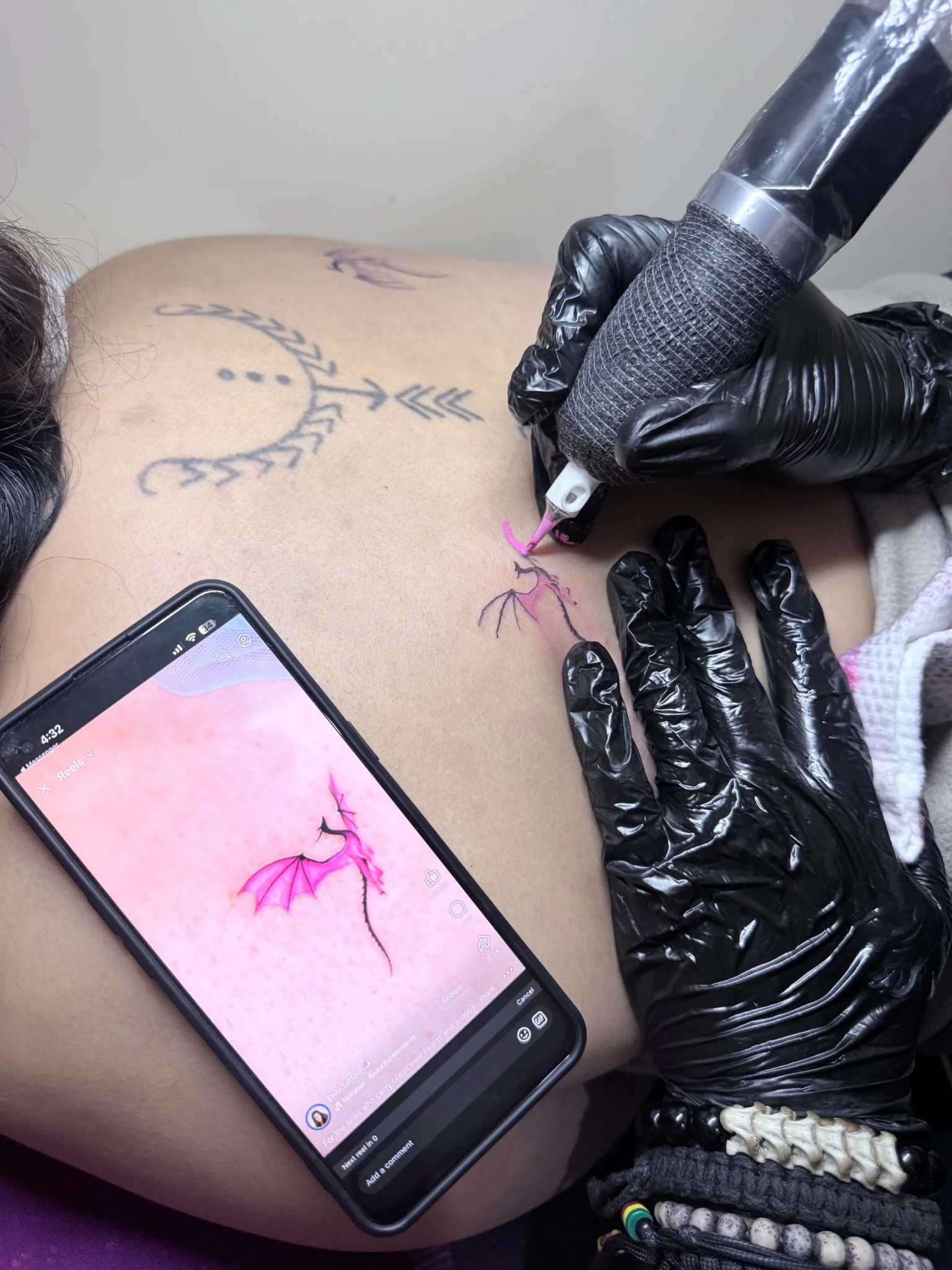 Colorful illustrative dragon tattoo being applied on back placement