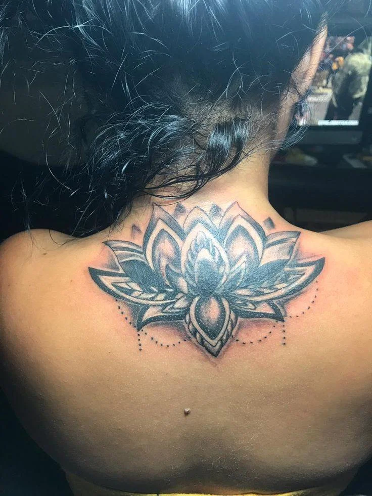 Black and grey lotus flower tattoo with ornamental mandala detailing on upper back