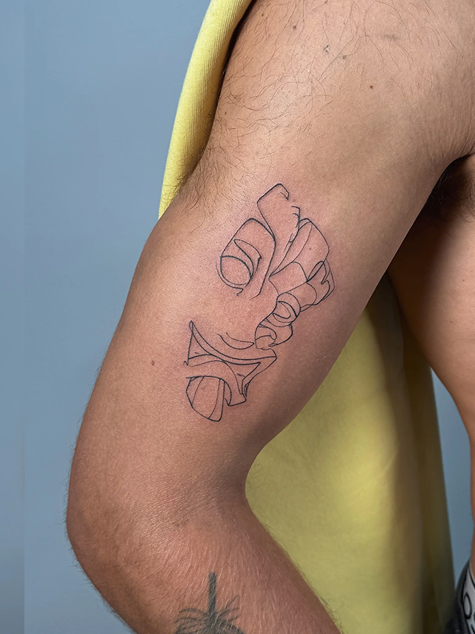 Fine line outline tattoo of a hand holding a flower on upper arm