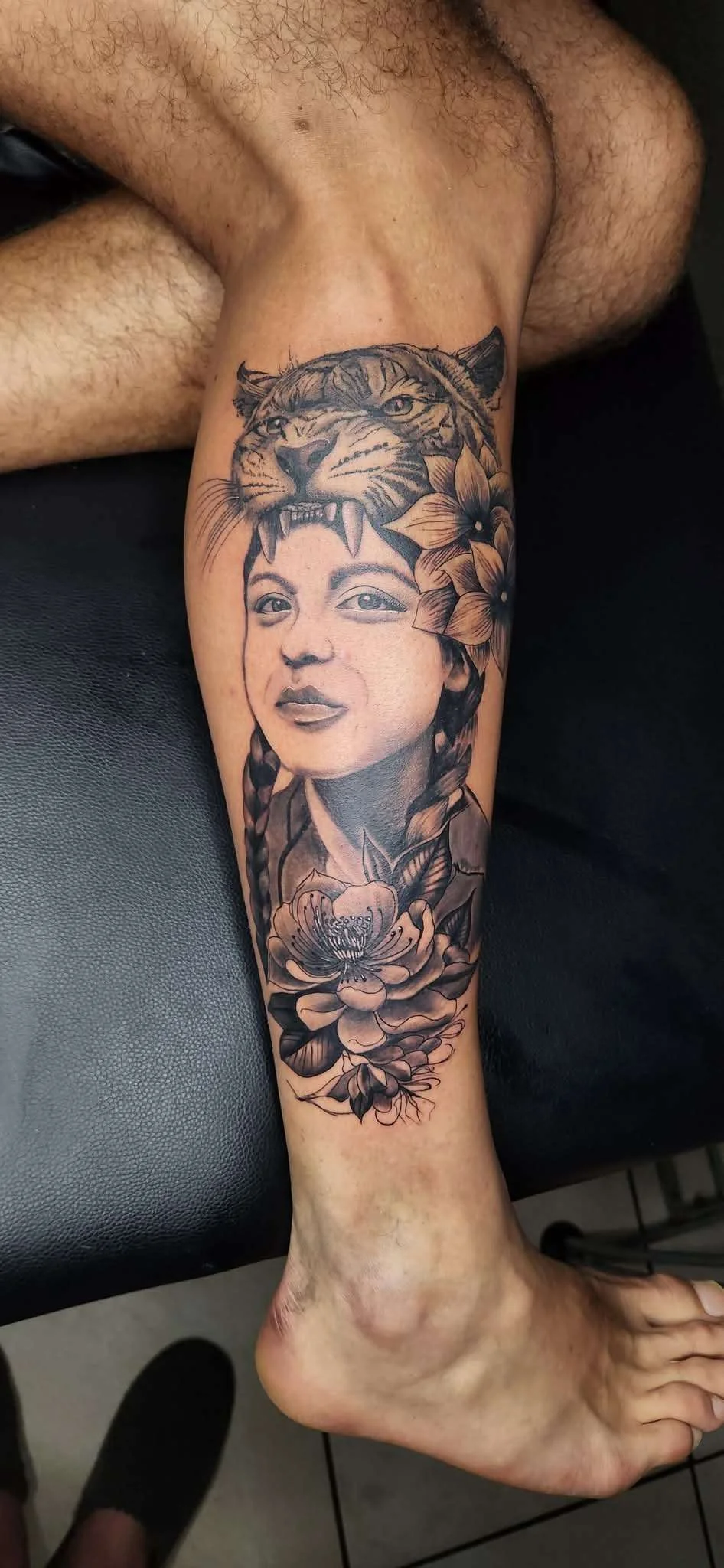 Black and grey realism portrait with tiger and floral elements on forearm